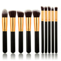 Das PRO Makeup Brush Set Black/Gold von PRO enthält 10 hochwertige Kabuki- und Präzisionspinsel mit schwarzen Griffen, goldenen Zwingen und weichen Borsten, die alle aufrecht in einer Reihe vor einem weißen Hintergrund angeordnet sind, um ein makelloses Auftragen zu gewährleisten.