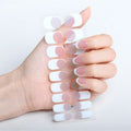 Eine Hand mit manikürten Nägeln hält UNIQ Semi Cured Gel Nail Stickers / Selbstklebender Nagellack – Classic French (JK-331) mit einem schicken Design in Weiß und Hellrosa, das perfekt zu den Nägeln passt.