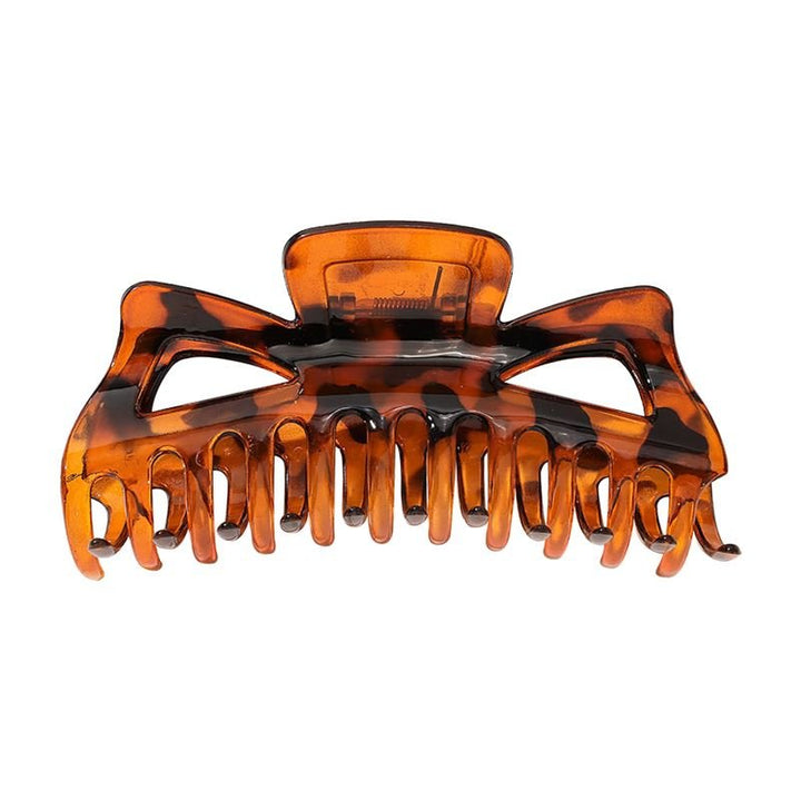 Die SOHO Astrid Hair Claw – Tortoise von SOHO ist eine stabile Haarspange mit Schildpattmuster, ineinandergreifenden Zähnen und Federscharnier, die auch dickes Haar den ganzen Tag lang sicher an Ort und Stelle hält.