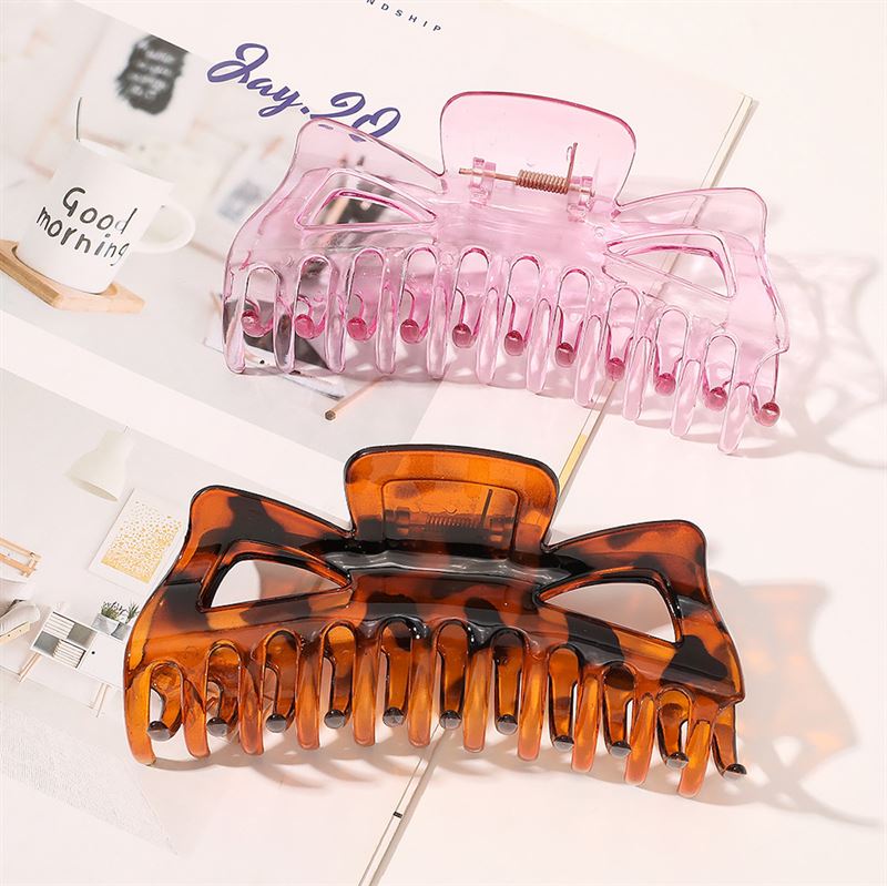 Zwei große SOHO Astrid Hair Claws, eine in Braun-Schildpatt und eine in durchscheinendem Rosa, sind auf einem aufgeschlagenen Magazin abgebildet. Im Hintergrund ist eine weiße Tasse mit der Aufschrift „Good morning” zu sehen.
