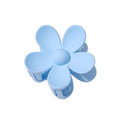 Die SOHO Bloom Hair Claw in Hellblau zeichnet sich durch eine glatte Oberfläche und ein abgerundetes Fünf-Blütenblatt-Design aus, das von oben zu sehen ist.