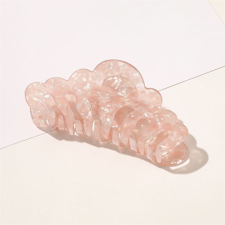 The SOHO Callie Hair Claw in Blush, a translucent pale pink clip with a marbled pattern, rests on a white surface with soft shadows.