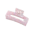 Die SOHO Clara Hair Claw – Lavender Pink ist eine große rechteckige Acrylklammer in Rosa und Weiß mit einer glänzenden, durchscheinenden Oberfläche und einem Federscharnier – ideal als XL-Haaraccessoire für dickes Haar.