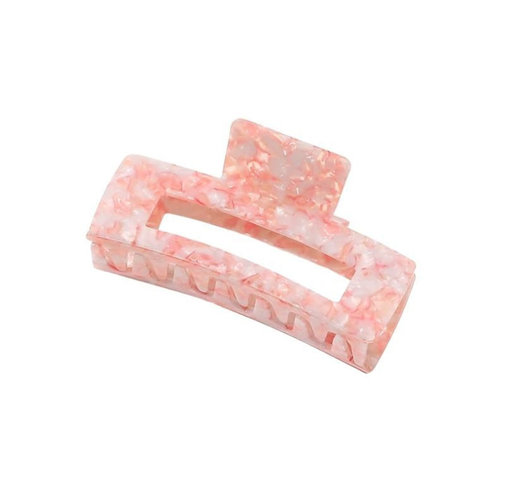 Die SOHO Clara Hair Claw – Light Coral ist eine XL-Haarklammer in rechteckiger Form mit einem rosa-weißen Marmormuster, einer Aussparung in der Mitte und ineinandergreifenden Zinken, ideal für dickes Haar, abgebildet vor einem schlichten weißen Hintergrund.
