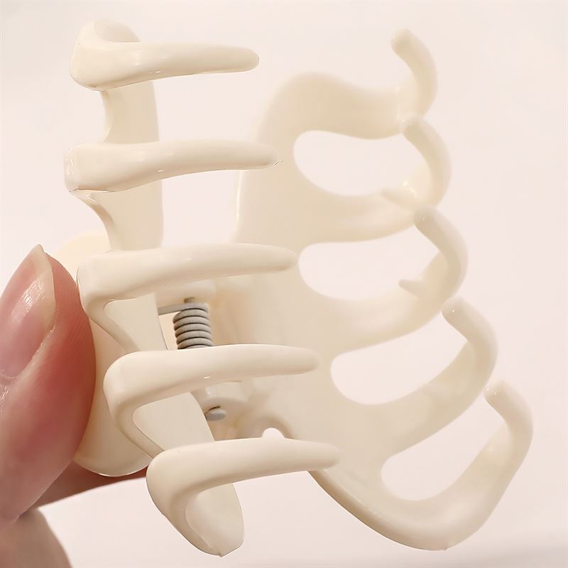 Nahaufnahme einer Hand, die die SOHO Esta Hair Claw in Grün hält, mit breiten, gebogenen Zinken und einer sichtbaren Metallfeder für sicheres Haarstyling und zusätzlichen Halt.