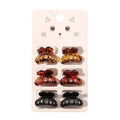 Die SOHO Fika Mini Hair Claws von SOHO umfassen sechs kleine Klammern in Gelb, Braun und Schwarz, die paarweise auf einer Karte mit einer niedlichen Katzenillustration angeordnet sind – perfekt für das tägliche Haarstyling.