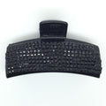 Die SOHO Hair Claw von SOHO ist ein schwarzes Haaraccessoire aus Kunststoff mit einem rechteckigen Verschluss mit Gitterstruktur, das auf einem schlichten weißen Hintergrund präsentiert wird.
