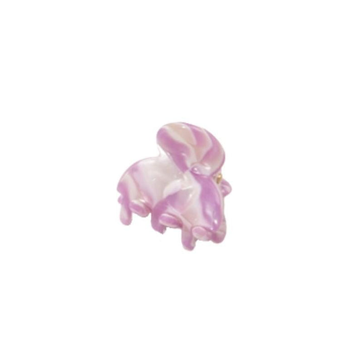 Eine SOHO Hara Mini-Haarklammer in Periwinkle wird neben einer kleinen, glänzenden rosa-weißen Glasfigur in Form eines Hasen gezeigt, beide vor einem schlichten weißen Hintergrund.