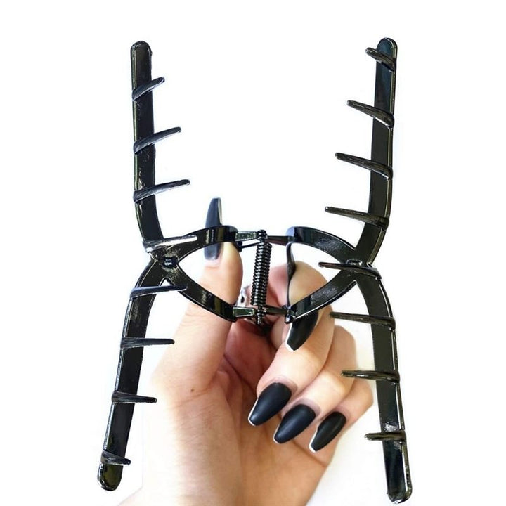 Eine Hand mit langen, mattschwarzen Nägeln hält die SOHO Iva Metal Hair Claw in Schwarz, ein großes Accessoire von SOHO mit weit auseinanderstehenden Zinken – perfekt zum Fixieren eines unordentlichen Dutts – vor einem weißen Hintergrund.