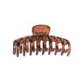 Die SOHO Kana Hair Claw – Tortoise ist eine große braune Kunststoffklammer von SOHO mit gebogenen Zinken und einem Federscharnier, die einen starken Halt für alle Haartypen bietet und Ihr Haar sicher und an Ort und Stelle hält.