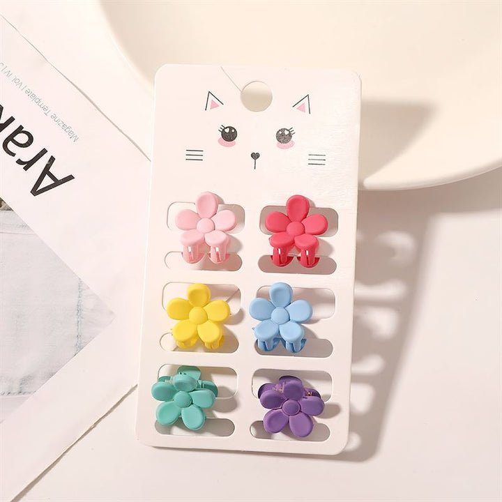 Die SOHO Lala Mini Hair Claws – Flowers von SOHO bestehen aus sechs bunten, blumenförmigen Mini-Haarklammern in Pink, Rot, Gelb, Blau, Grün und Lila, die auf einer weißen Karte mit einer niedlichen Katzenillustration präsentiert werden.