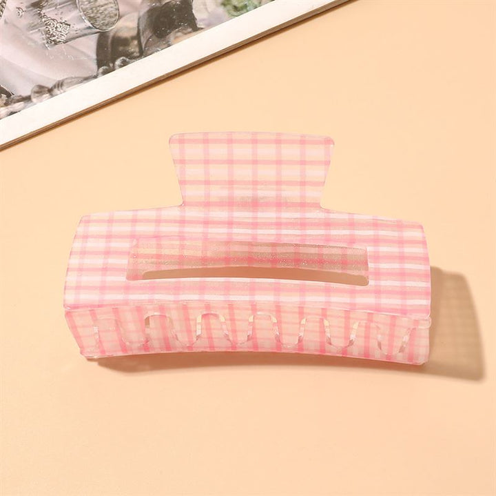The SOHO Line Hair Claw - Pink by SOHO features a large chequered pattern, shown on a beige surface by a photo corner, offering a stylish and secure hold for your hair.