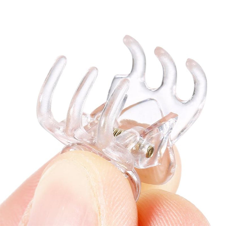Eine Nahaufnahme von Fingern, die eine SOHO Lucca Mini Hair Claw halten – transparent, mit vier Zinken und einem Metallfederscharnier – perfekt für Fans der Mini-Haaraccessoires von SOHO.