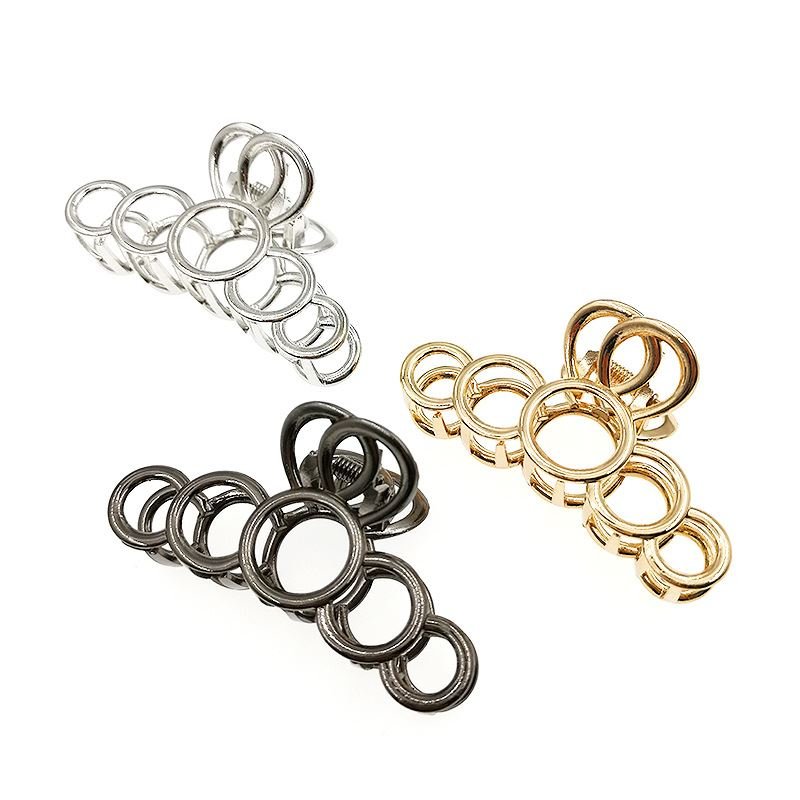 Die SOHO Metal Hair Claw in Silber von SOHO besteht aus ineinandergreifenden Metallringen unterschiedlicher Größe, die dickes Haar stilvoll und elegant fixieren, und wird auf weißem Hintergrund präsentiert.