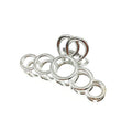 Sieben glänzende Metallringe unterschiedlicher Größe, inspiriert von den eleganten Kurven der SOHO Metal Hair Claw – Silver von SOHO, sind wie eine Raupe auf einem weißen Hintergrund in einer Linie angeordnet.