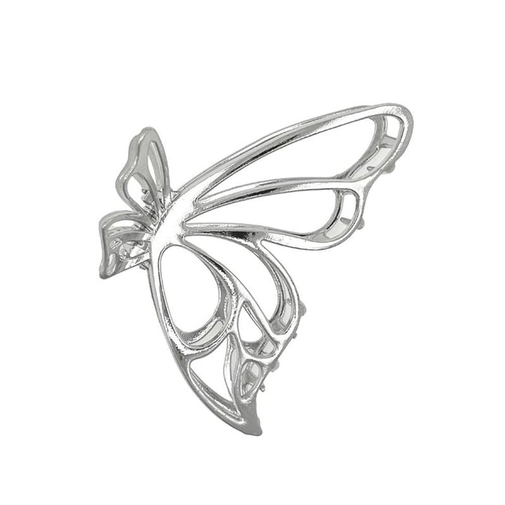 Die SOHO Nabi Hair Claw in Silber von SOHO zeichnet sich durch ein filigranes, durchbrochenes Schmetterlingsdesign mit dünnen, geschwungenen Linien aus, die die Flügel und den Körper bilden und sich wunderschön vor einem weißen Hintergrund abheben.