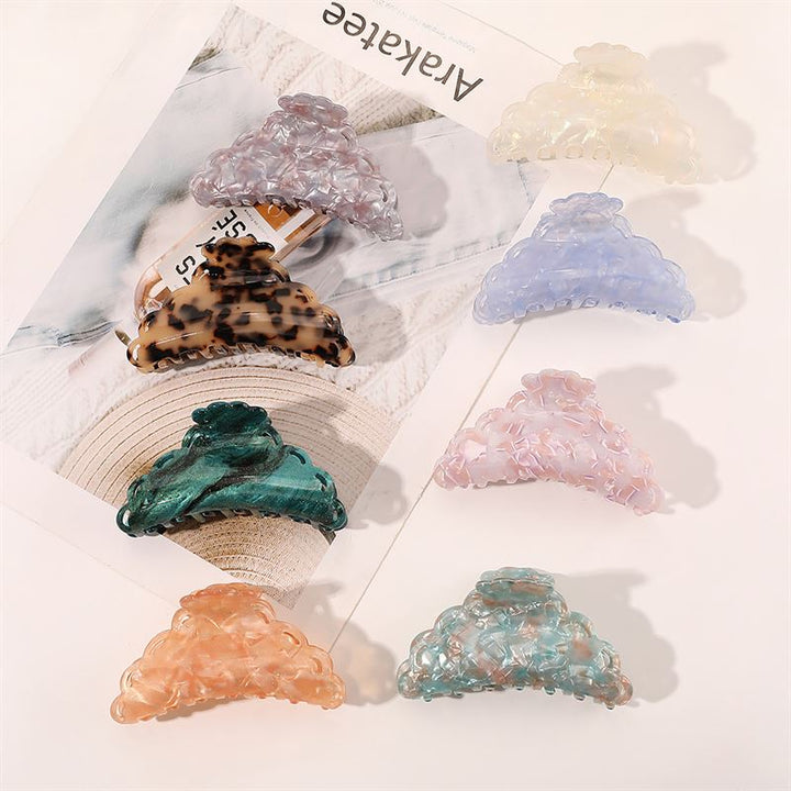 Seven SOHO Naomi Hair Claw – Sunshine-Clips von SOHO mit verschiedenen Mustern und Pastelltönen werden auf einer weißen Oberfläche und in einem Magazin präsentiert – perfekte, farbenfrohe Accessoires, die jede Frisur aufwerten.