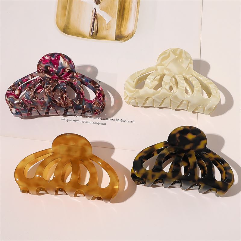 Vier SOHO Olivia Hair Claws, darunter marmoriertes Rosa, Creme, Bernstein und eine dunkle Schildpatt-Klammer, sind auf einer Fläche angeordnet. Jede Klammer von SOHO wirft unter sanftem Deckenlicht sanfte Schatten.