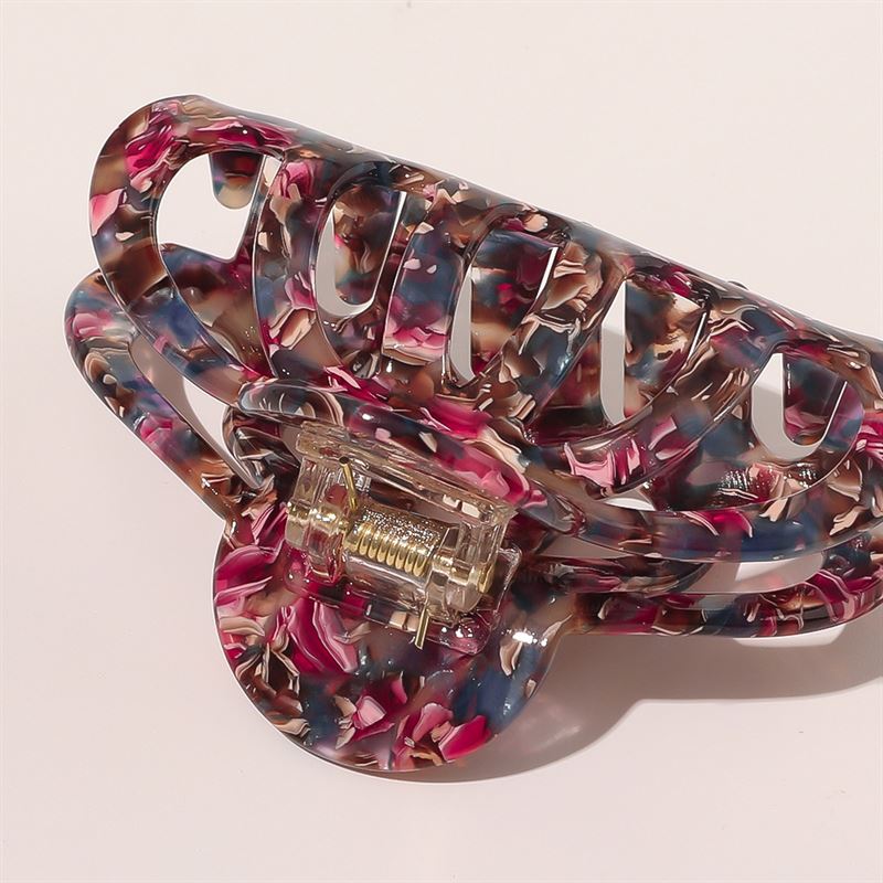 Eine Nahaufnahme der SOHO Olivia Hair Claw – Dark Tortoise, einer großen marmorierten Haarspange in satten Braun- und Bernsteintönen mit einem robusten Metallscharnier, vor einem einfarbigen hellen Hintergrund.