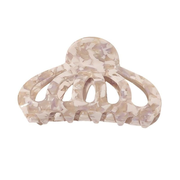 Die SOHO Olivia Hair Claw – Marble ist ein beige-weiß marmoriertes Accessoire mit abgerundeter Spitze, geschwungenem, offenem Design und breiten Zinken für sicheren Halt im Haar.