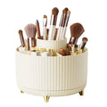Der UNIQ Rotating Makeup Organiser in Cremeweiß verfügt über ein gestuftes, geripptes Design mit Fächern und goldenen Beinen und bietet einfache Aufbewahrung und Organisation für Pinsel, Lippenstifte, Stifte und Beauty-Produkte.